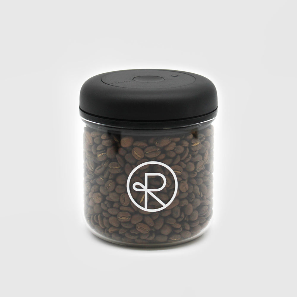 Fellow Atmos Vacuum canister with Reborn Coffee logo imprinted on glass, filled with coffee beans. Black, twist seal top with 0.7 liter glass canister. 1 of 5.