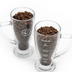 
                  
                    Two Reborn Coffee pint glasses, side by side, filled with coffee beans. 1 glass shows the Reborn Coffee circular logo, the other glass shows the text, “I’m feeling, Not ready, A little better, almost there, Reborn.” 4 of 4.
                  
                