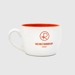 
                  
                    White ceramic cup with orange interior, has Reborn Coffee circular logo and text that reads, “The first reborn cup, limited.” Has a handle. 1 of 4.
                  
                
