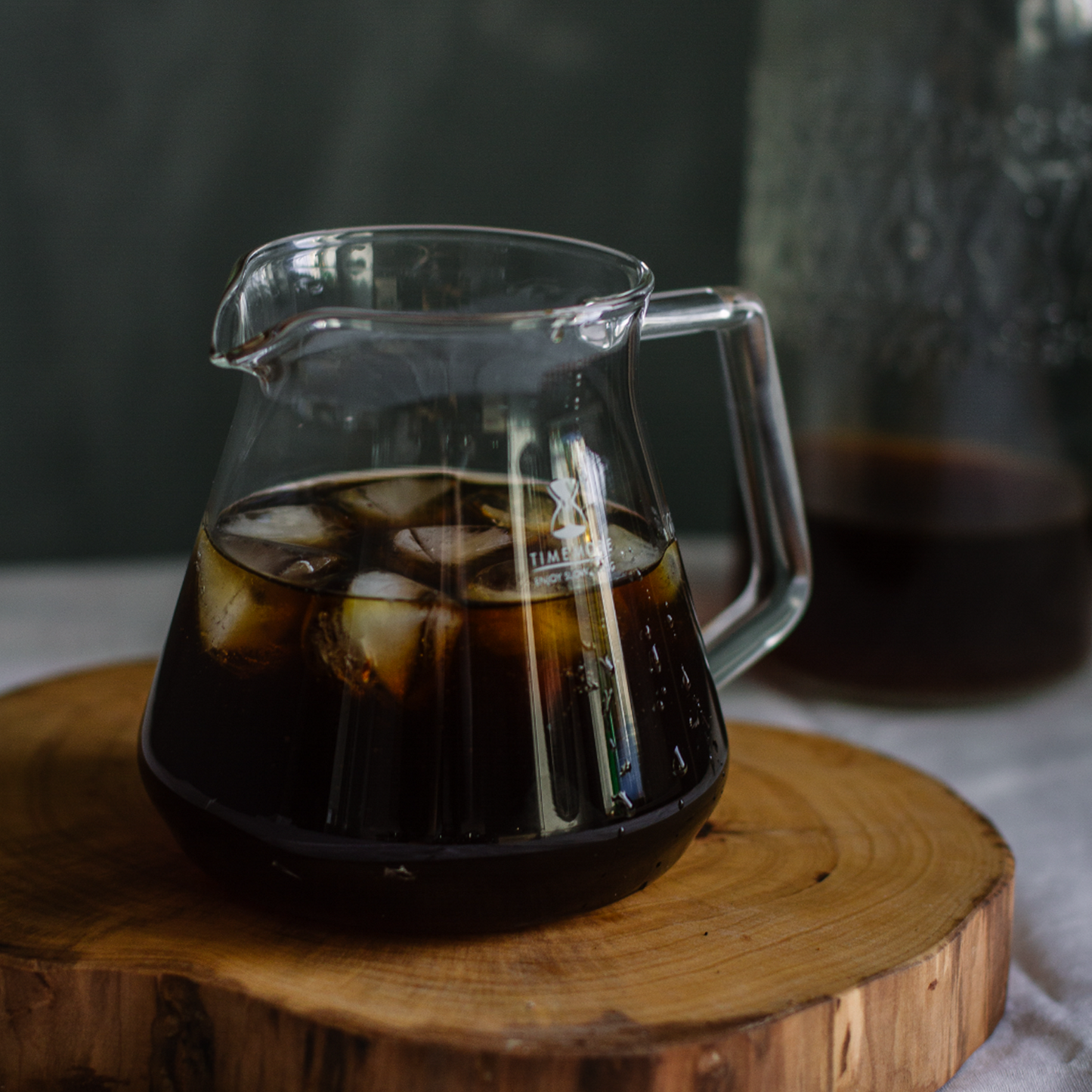 Cold brewed coffee in a timemore glass pitcher with ice cubes. Nearly empty pitcher of cold brew in background. 7 of 9.