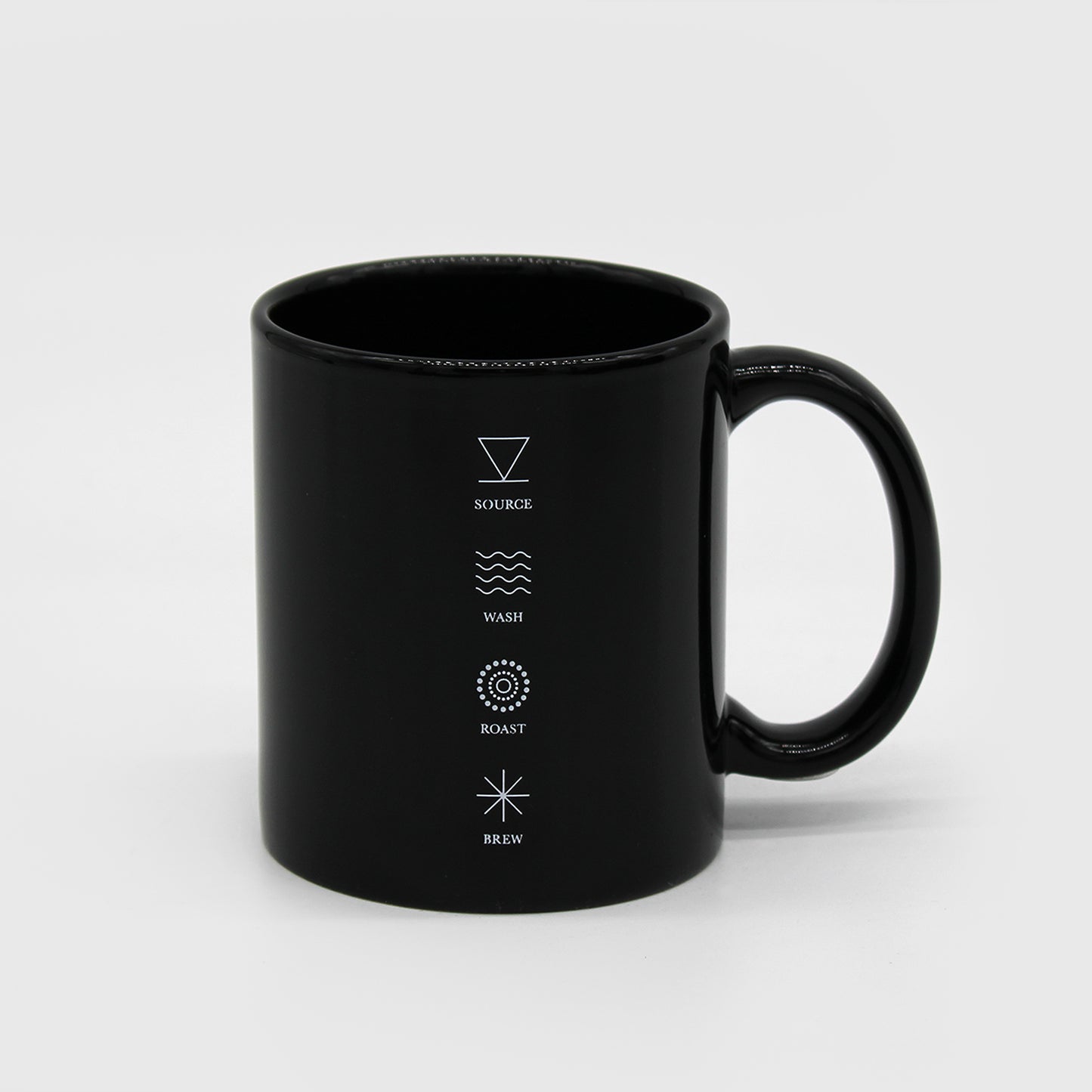 Black Ceramic mug with C handle, has 4 symbols aligned vertically, with text under each symbol that reads, “Source, Wash, Roast, Brew.” 1 of 3.